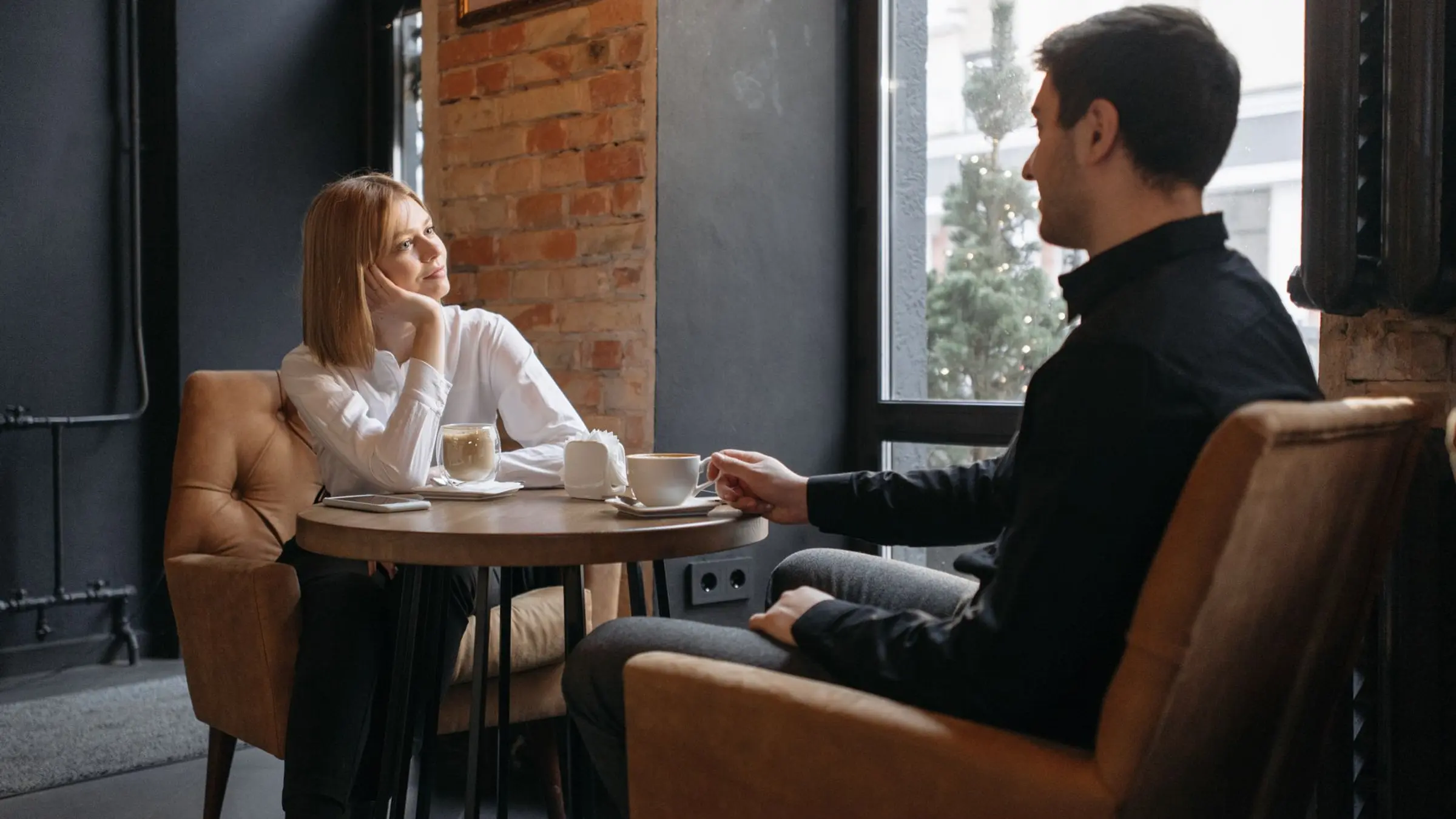 A calm couple sitting together in a warm room while having an honest relationship conversation.