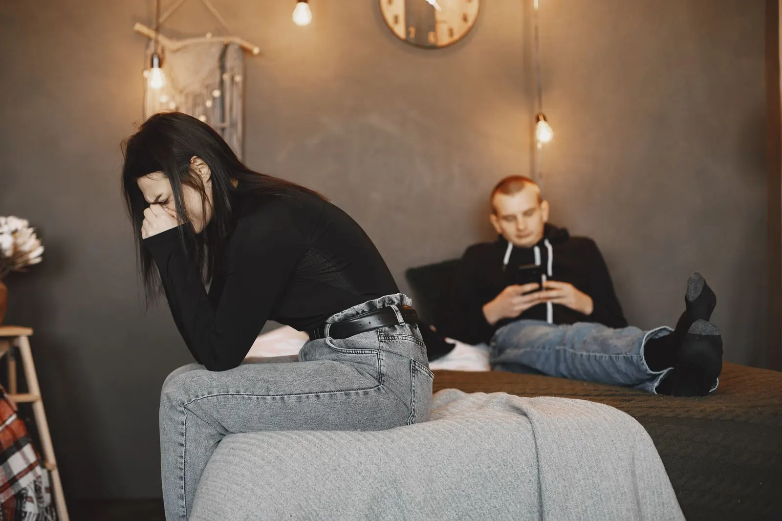 A couple in emotional distance while one person holds a phone during a difficult relationship moment