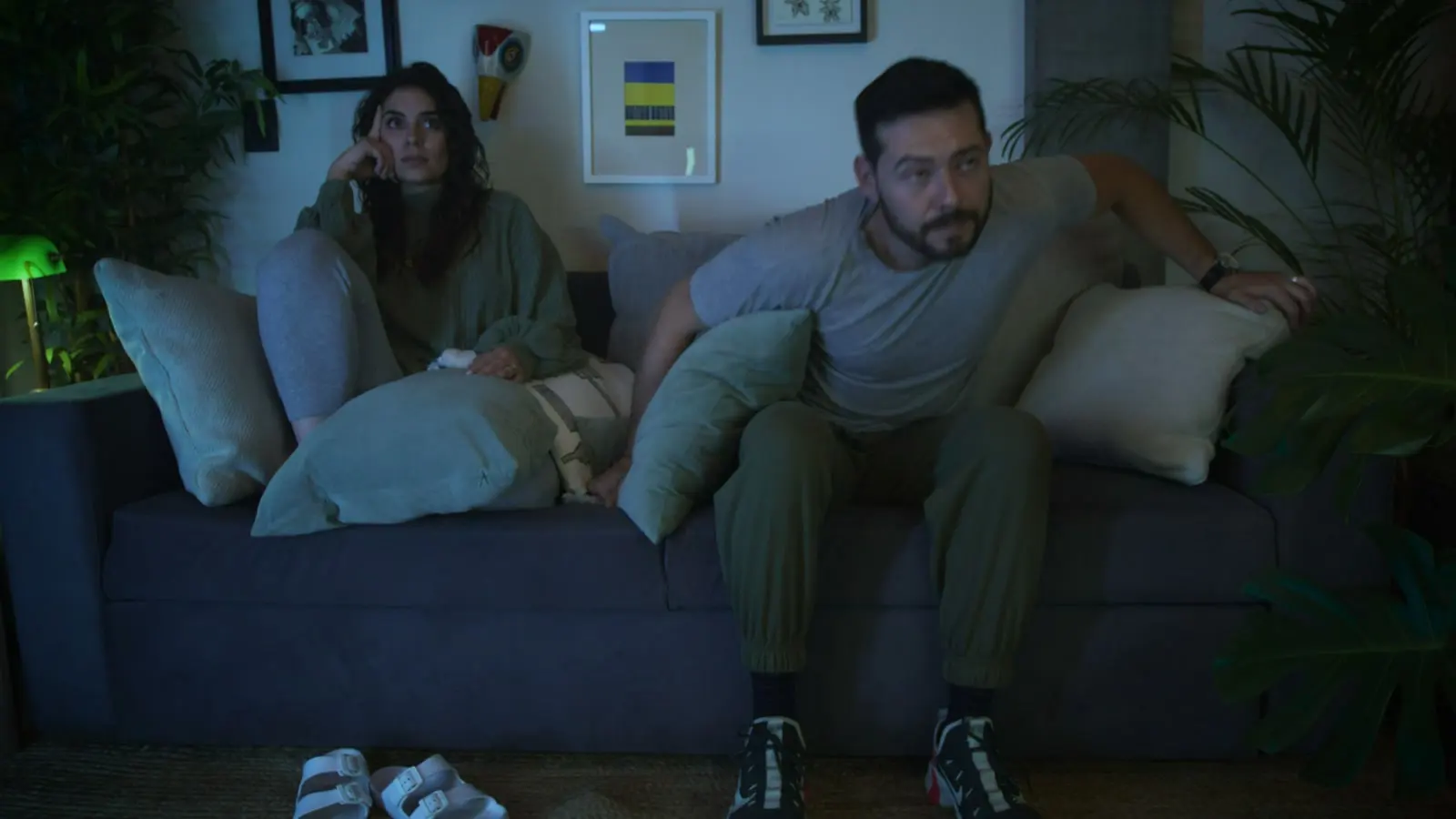 Two people sitting apart on a sofa during a tense quiet moment