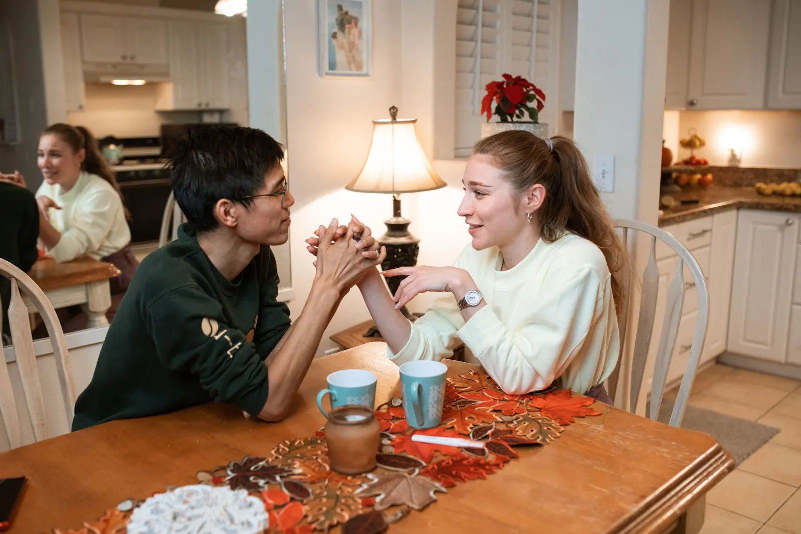 A couple holding hands at a kitchen table during a calmer repair conversation