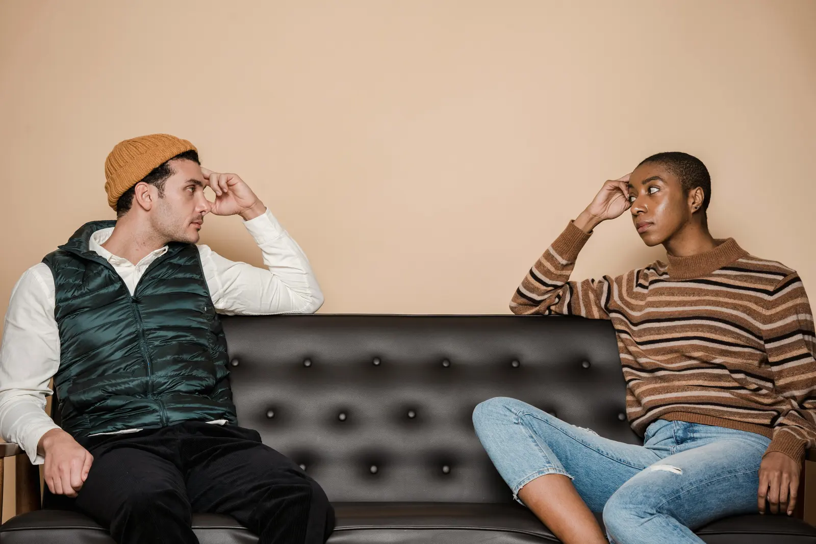 A couple sitting apart on a couch while pausing a tense conversation