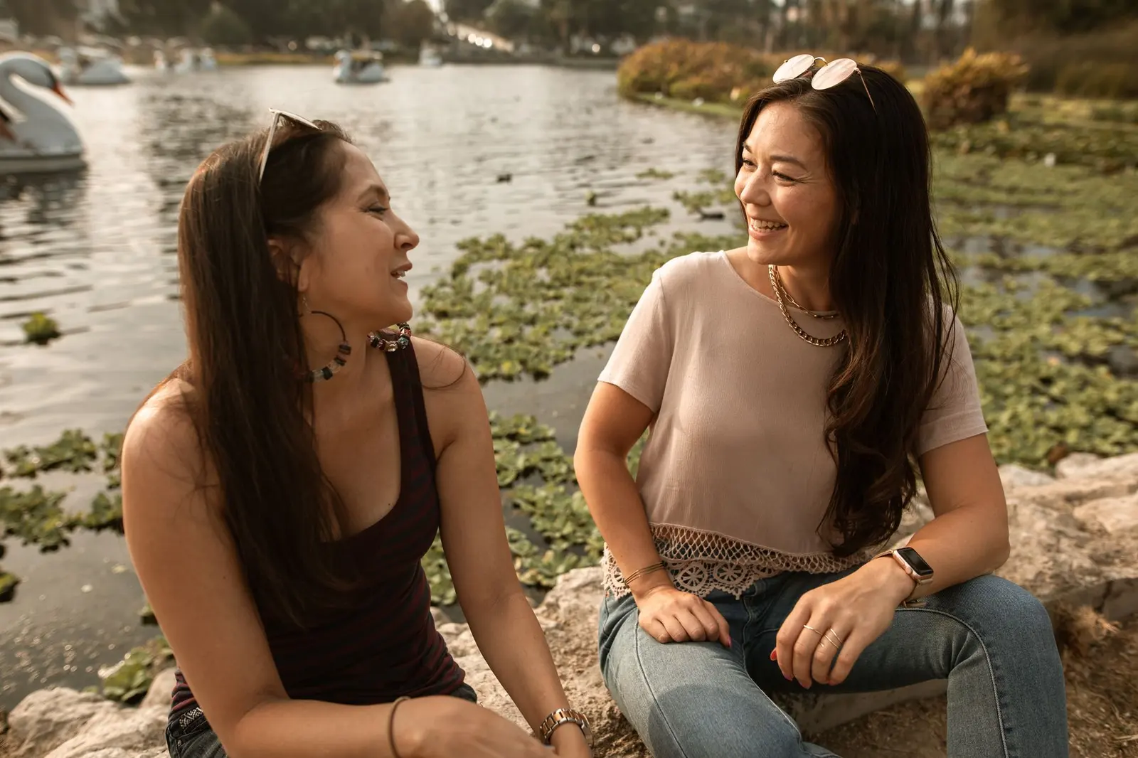 Two women smiling by a lakeside during a warm, supportive conversation.