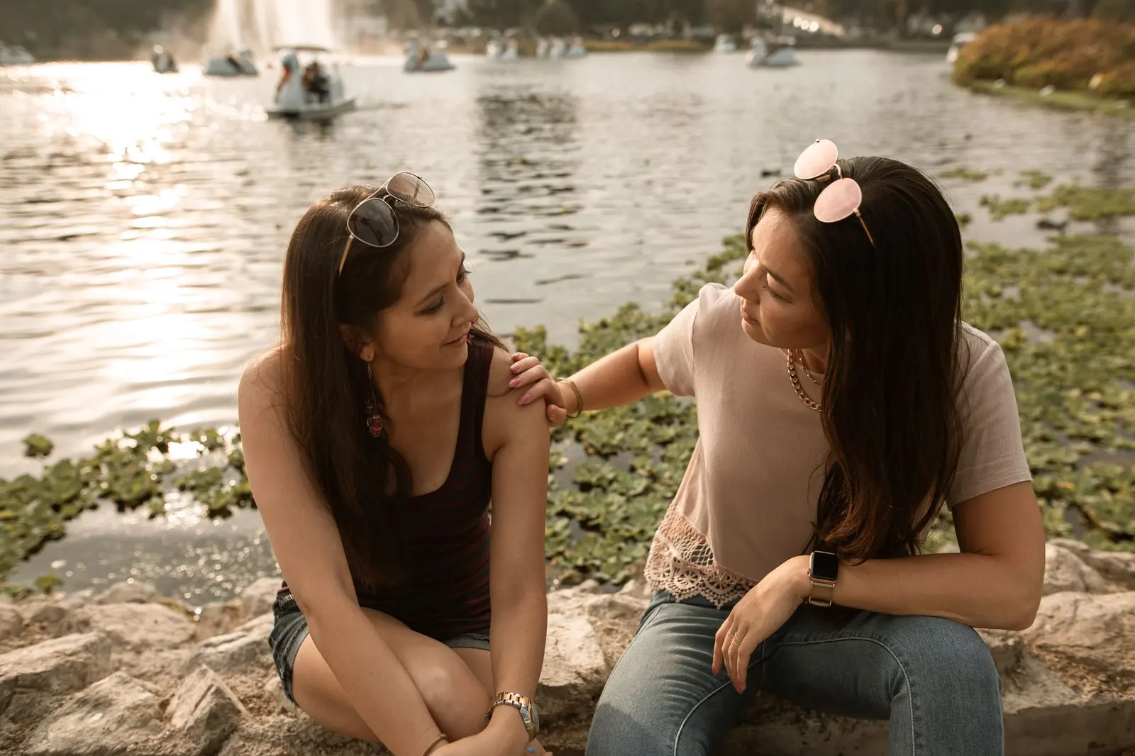 Two women sitting beside a lake in a gentle heart-to-heart conversation.