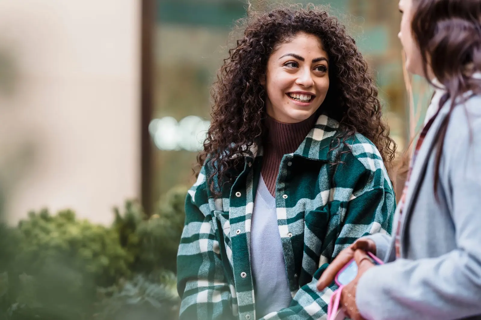 Two women talking outside in daylight with an easy, open expression.