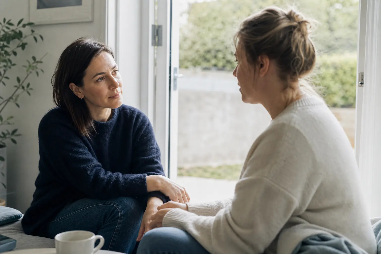 Two women having a calm supportive conversation beside an open doorway