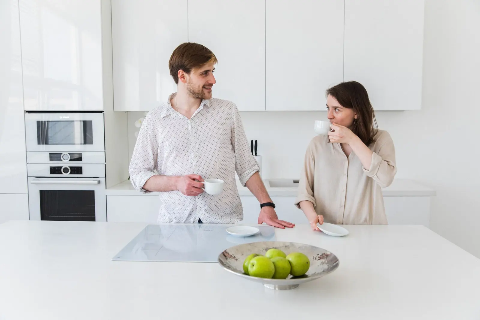 A couple sharing a quiet kitchen moment while keeping the conversation light.