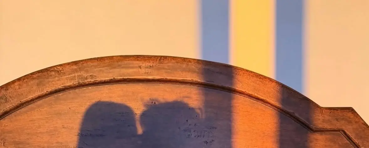 Warm shadows of two people close together, suggesting memory and longing without text.