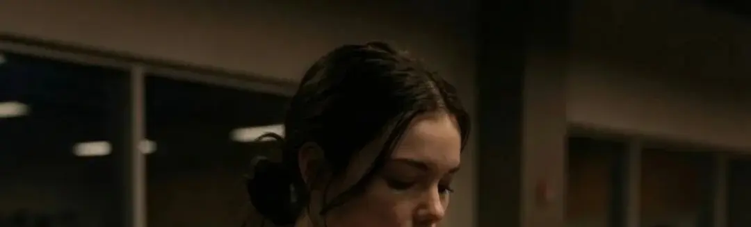 A person looking down in a dim indoor setting, suggesting uncertainty after a vague message.
