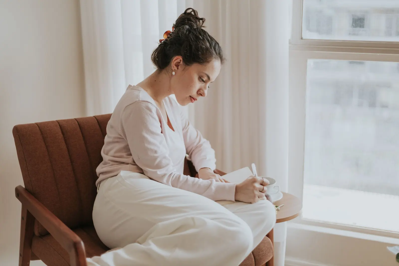 Why Is My Boyfriend So Mean to Me? Signs and What to Do: a person journaling beside a window while reflecting